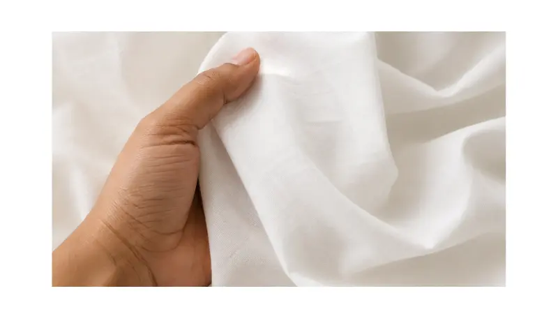 Hand holding white cotton fabric